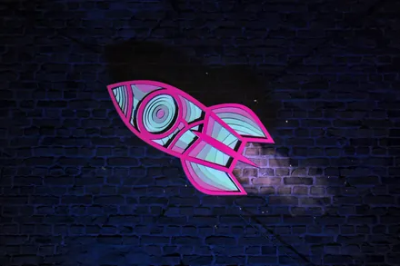 The same rocket on the brick wall, in hot pink and light blue