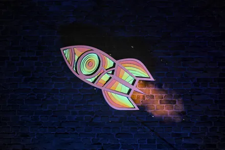 The same rocket on the brick wall, in green, orange and pale pink
