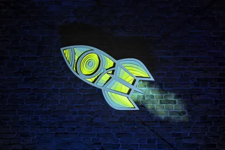 The same rocket on the brick wall, in blue and yellow-green