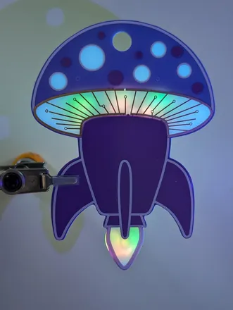 The finished kit: a mushroom cap on a rocket body, backlit by LEDs in blue and green