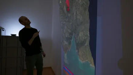 A visitor pointing a laser at the 3D-printed alpine terrain